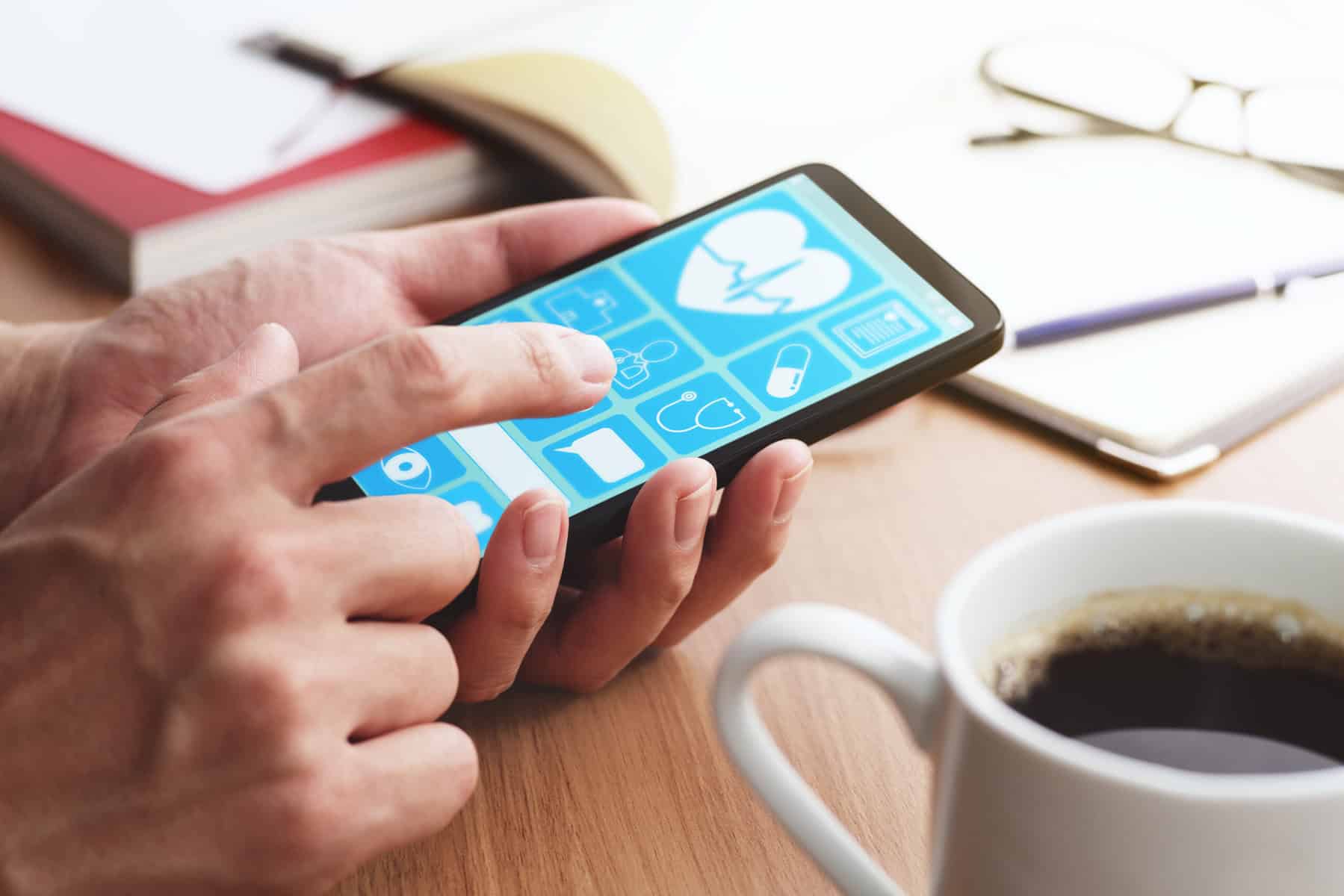 Closeup of male hands touching smartphone screen at table.