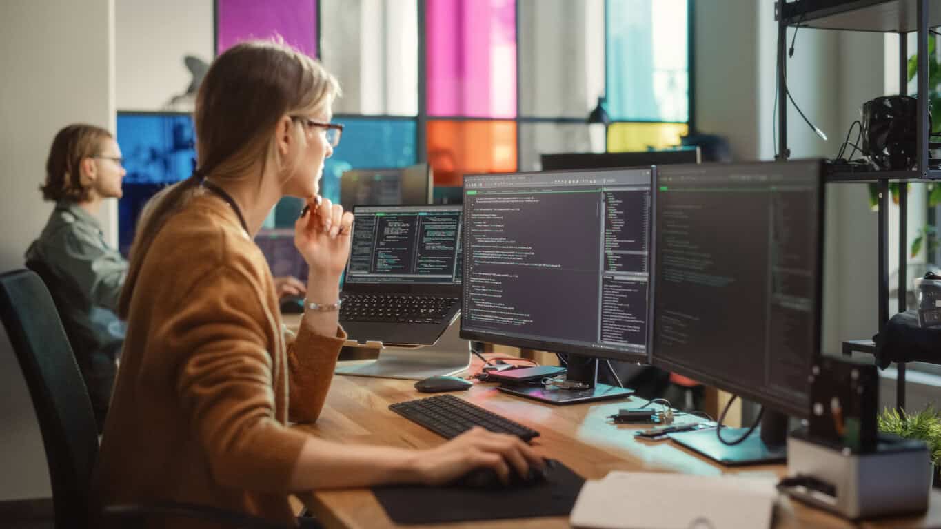 Professional Female Backend Software Developer Coding on Desktop Computer With Two Displays in Creative Office.